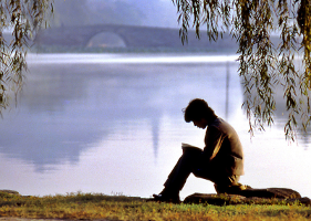 A man reading by a lake.